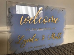 Clear Acrylic Wedding Welcome Sign in Gold Writing on Pale blue Background